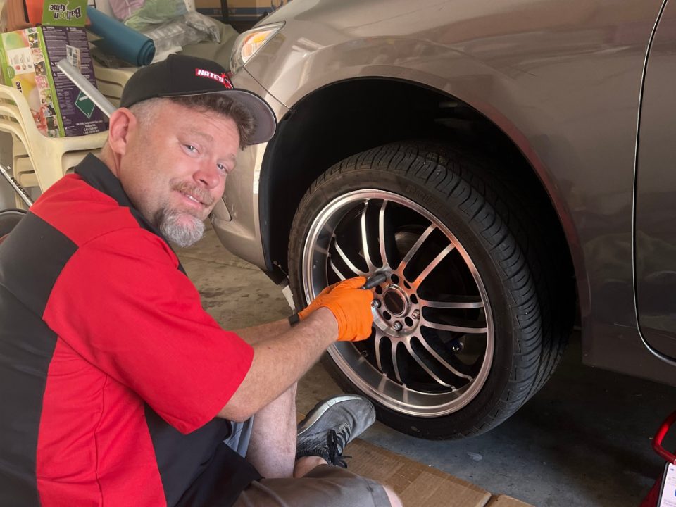 Nate Hauger, owner of Nate&rsquo;s Brakes, working on a car wheel